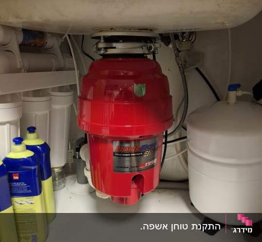 מתקן אדום מתחת לכיור עם צינורות ומיכלים